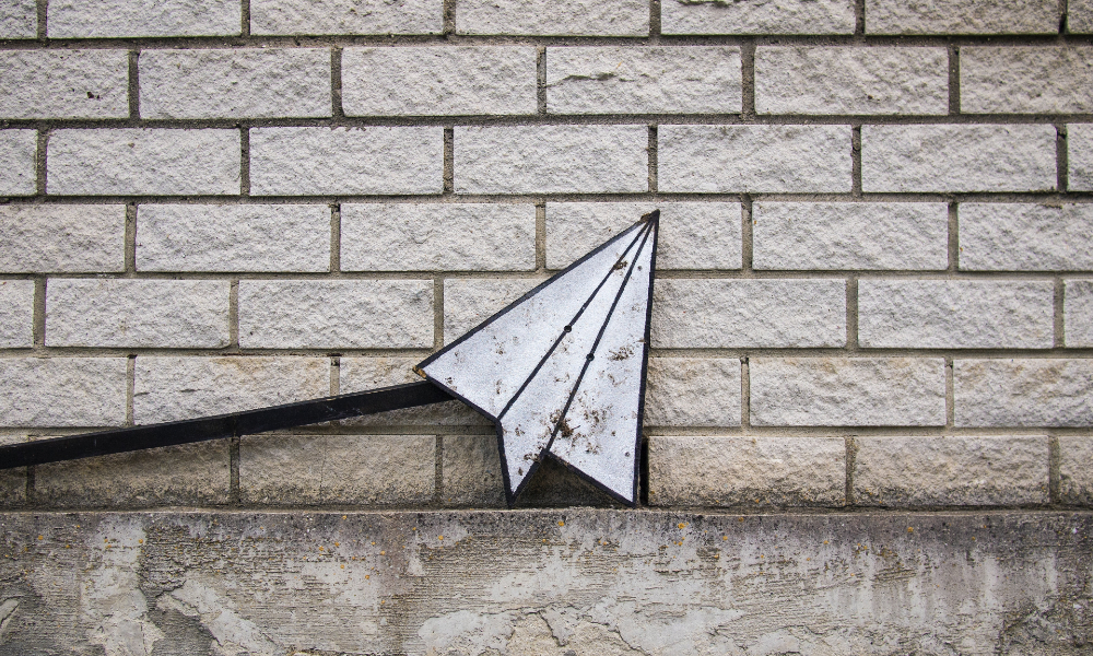 A stylized paper airplane in front of a gray brick wall, Photo by Daria Nepriakhina from Unsplash